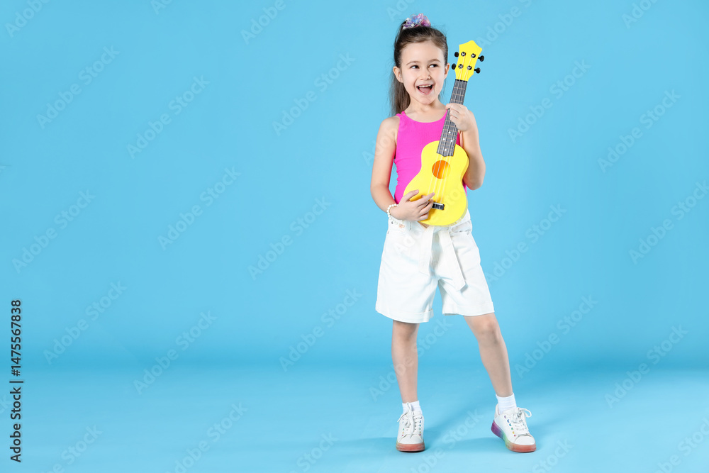 Fototapeta premium Cute girl playing toy guitar on light blue background