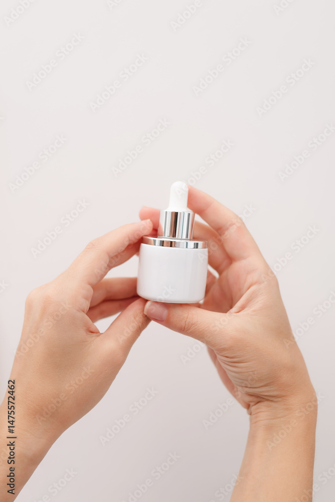 Woman hands holding facial serum on white background Woman hands holding facial serum on white background