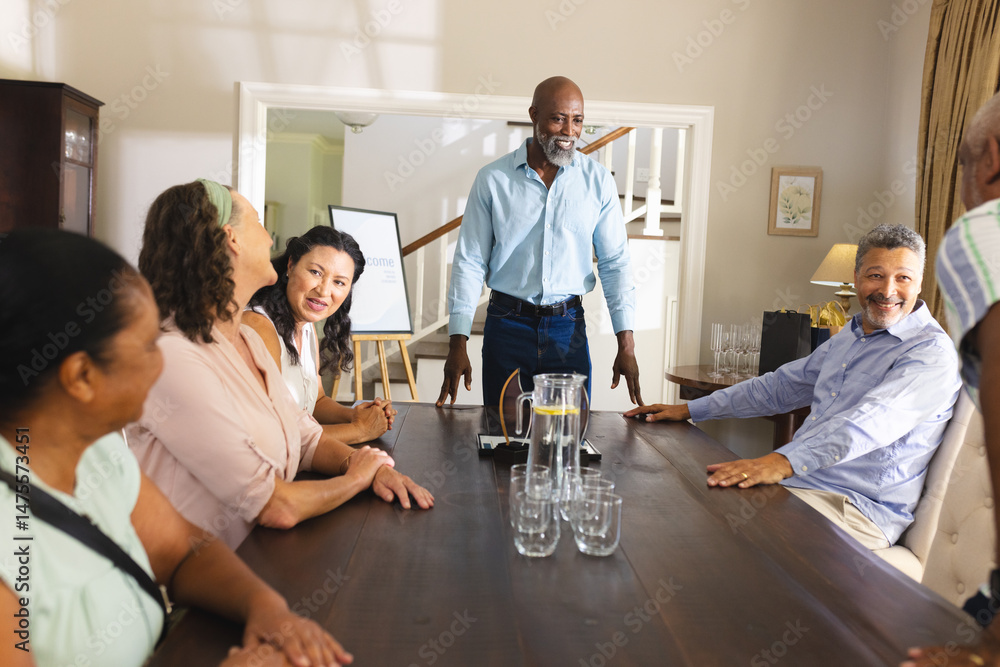 Obraz premium Celebrating with friends, African American man standing and smiling at dining table