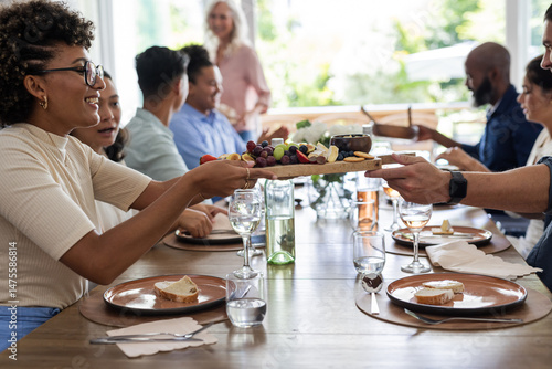 At wedding reception, friends sharing charcuterie board, chatting and savoring food