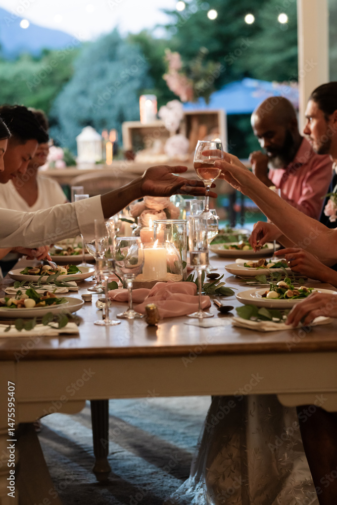 Fototapeta premium Guests toasting with wine glasses at elegant outdoor wedding dinner table