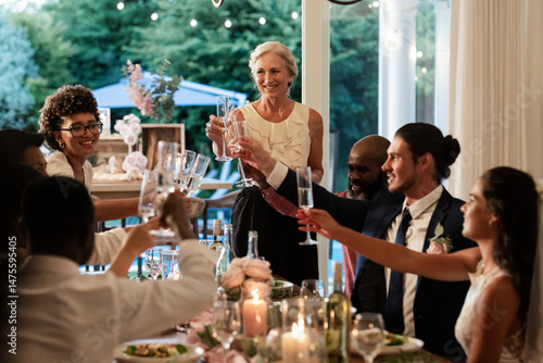 Guests raising glasses in joyful toast at elegant wedding reception dinner