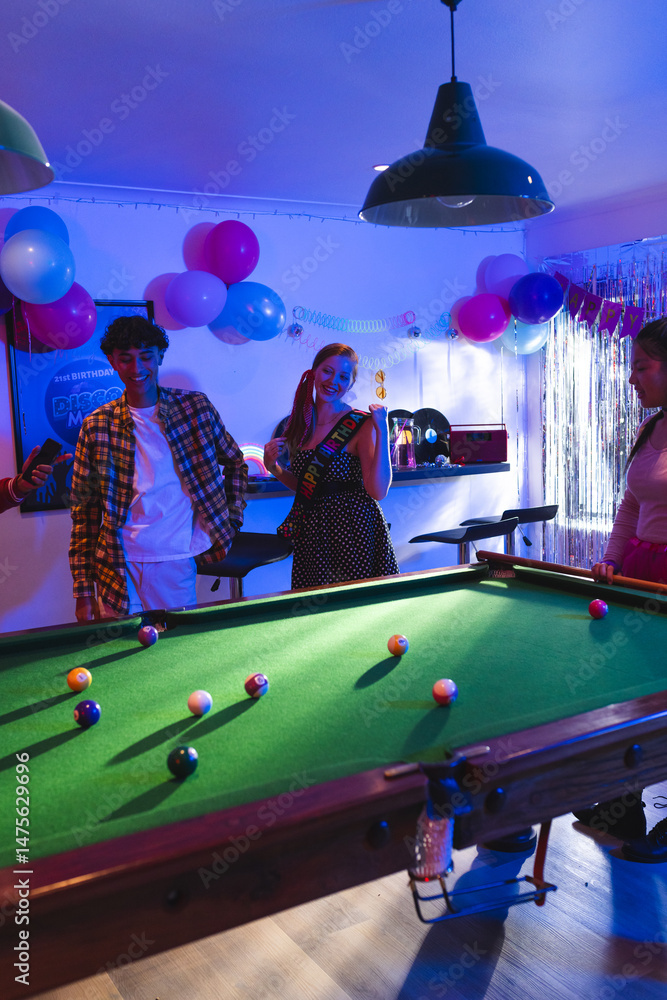 Fototapeta premium Teenagers enjoying birthday party playing pool in festive decorated room