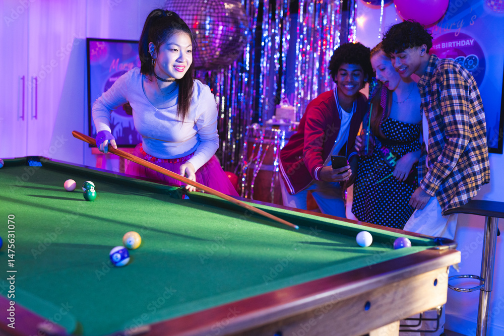 Naklejka premium Teenagers playing pool at birthday party, enjoying celebration with friends