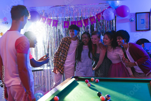 Teen friends posing for group photo at birthday party near pool table
