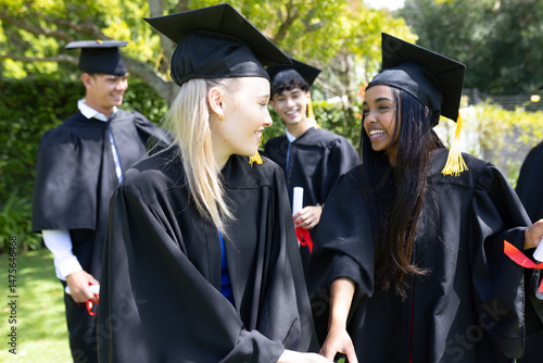 Graduating students celebrating in caps and gowns, smiling joyfully outdoors