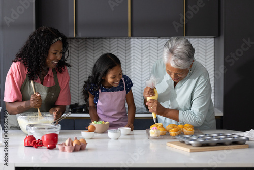 Three generations baking cupcakes together in modern kitchen, sharing joyful moments