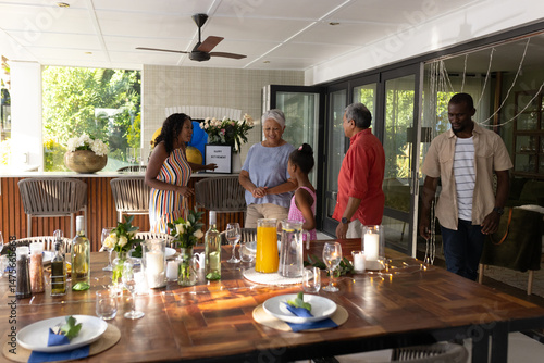 On patio, three generations sharing laughter and conversation during family gathering