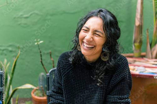 Portrait of a cheerful mature hispanic woman having fun and showing sincere emotions while smiling in a garden with plants