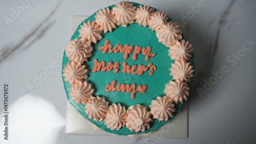 Close up of a beautifully decorated cake with pink floral icing and blue text reading 