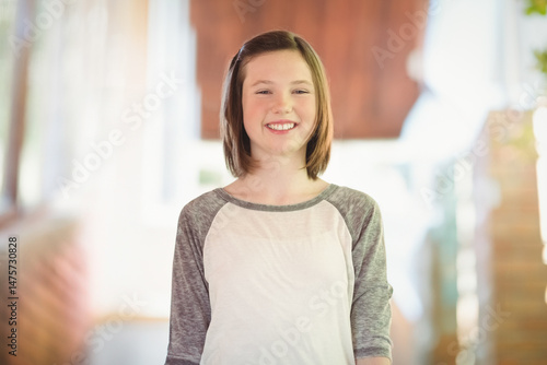 Teenage girl is standing in sunlit home interior near blurred window, showcasing gray-white shirt Free Download Teenage girl is standing in sunlit home interior near blurred window, showcasing gray-white shirt - GFXLoad