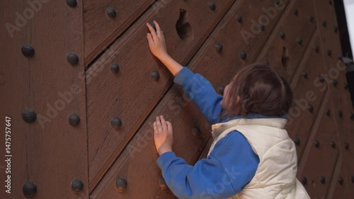 Girl exploring a historic wooden door with large nails