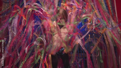 Person enjoying a colorful party decoration with ribbons