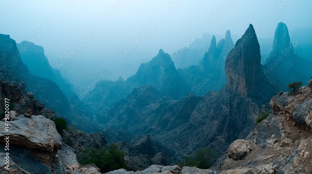 Naklejka premium Majestic Mountain Peaks Shrouded in Mist Capturing the Beauty of Nature's Rugged Terrain at Dawn in a Serene Atmosphere