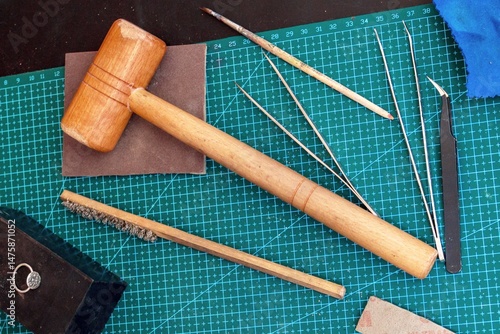 Overhead view on jewelcrafting tools on a green cutting mat in jewelry workplace. 