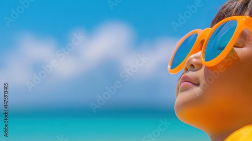 Obraz na płótnie A joyful child smiles while wearing bright orange sunglasses, soaking up the sun by the beautiful beach on a clear day w salonie