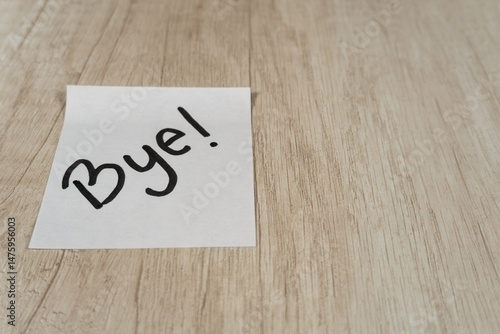 “Bye” written in black marker pen on a sticky note positioned on the left side