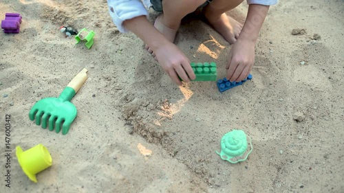 Adorable little boy having fun on a playground on bright sunny summer day. Cute child playing in a sandbox. Summer outdoor activities for family with kids.