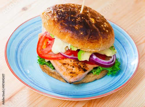 Delicious fish burger with juicy trout fillet, vegetables and avocado