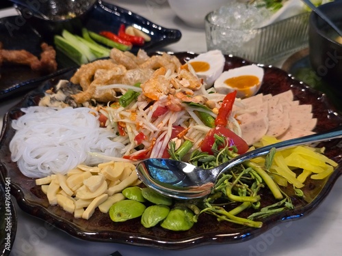 Thai papaya salad with side dishes including salted egg, pork caps, and various fresh vegetables, is a very popular local dish among Thais 