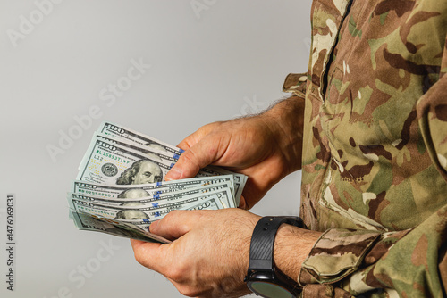 Soldier holding cash in military attire at indoor setting
