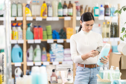 Wallpaper Mural European woman scans the barcode of a bottle of shampoo and shower gel on smartphone, she reads the composition and environmental friendliness of the products. Buyer pays through the online app and Torontodigital.ca