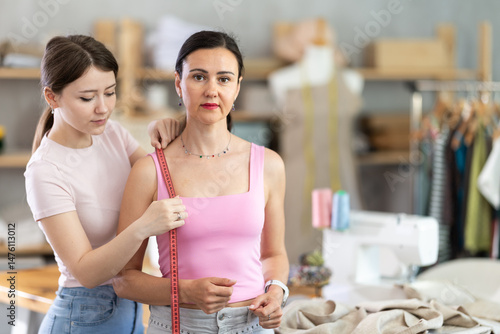 Принти на полотні Girl tailor takes measurements from woman client, using tape measure, measures body size for custom-made dress
