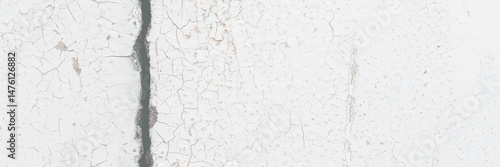 White peeling paint on the wall. Old concrete wall with cracked flaking paint. Weathered rough painted surface with patterns of cracks and peeling. High resolution texture for background and design.