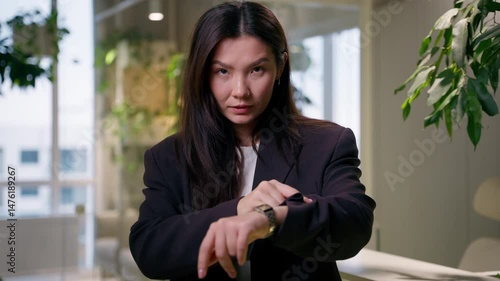Asian serious business woman looking at camera businesswoman pointing wristwatch wait meeting check time hurry deadline punctuality in office Chinese Korean Japanese girl appointment hand clock timing