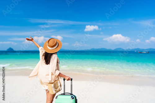 Young woman traveler with luggage relaxing and enjoying at beautiful tropical sand beach, Summer vacation and Travel concept