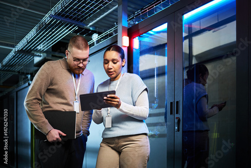 Wallpaper Mural Two professionals discussing data security strategies in modern server room with tablet. Collaboration between team members in a high-technology environment Torontodigital.ca