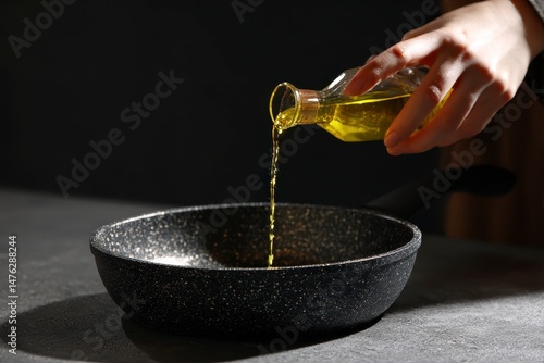 Obraz na płótnie Woman pouring oil into frying pan at dark gray textured table against black background w salonie
