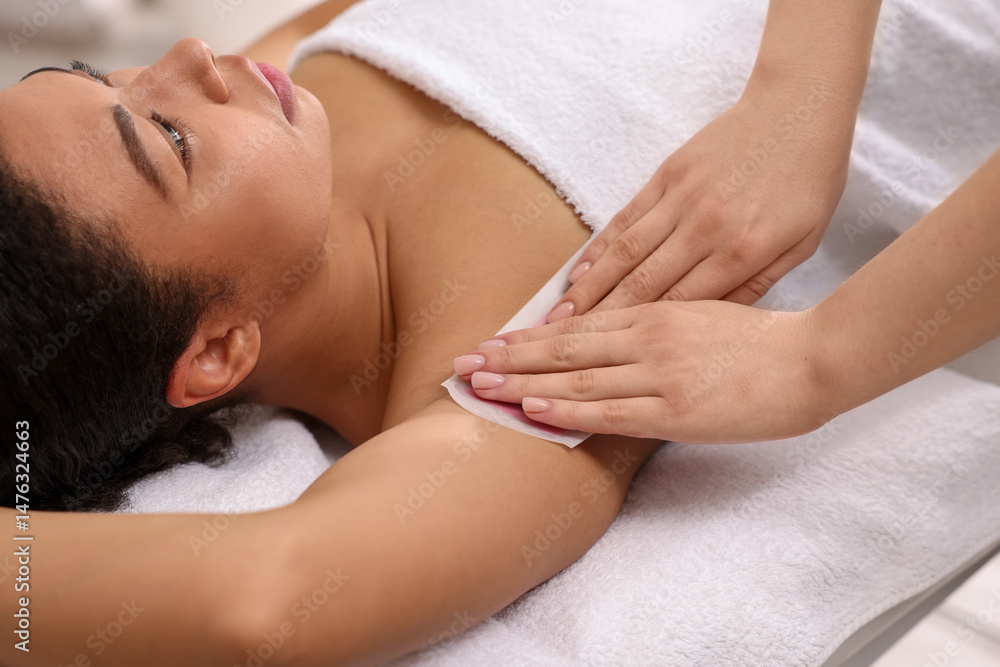 Woman undergoing wax epilation procedure in beauty salon Woman undergoing wax epilation procedure in beauty salon