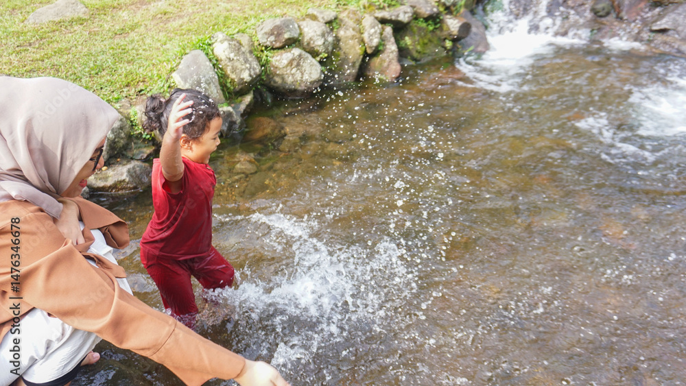 A daughter playing in a river with red clothes with her mother A daughter playing in a river with red clothes with her mother