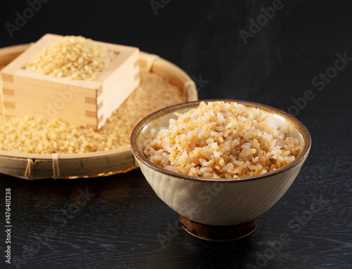 Freshly Cooked Brown Rice on a Black Background, with Brown Rice in a Strainer Behind