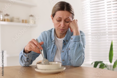 Slika na platnu Depressed woman with appetite loss at table indoors