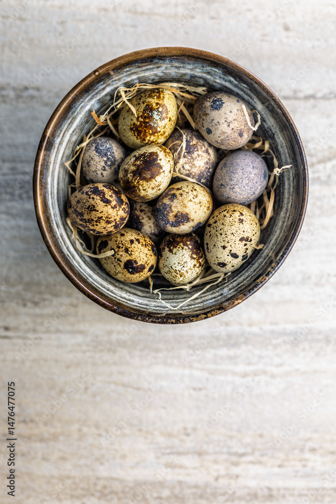 Spotted quail eggs in bowl on kitchen table. Top view.