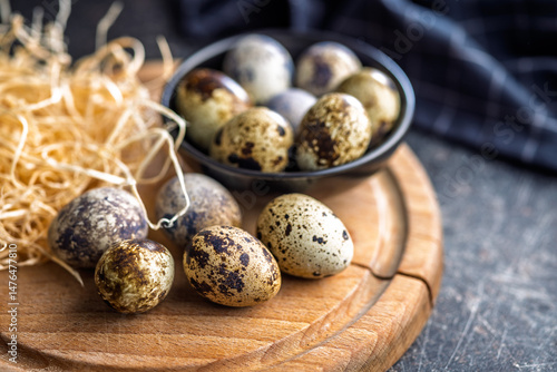 Obraz na płótnie Spotted quail eggs on wooden cutting board on black table. w salonie