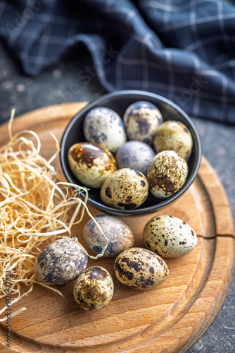 Obraz na płótnie Spotted quail eggs on wooden cutting board on black table. w salonie