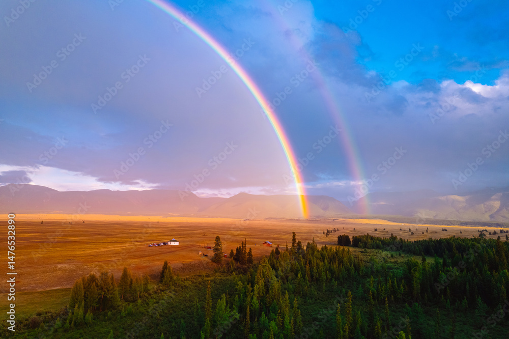 Naklejka premium Stunning double rainbow over serene countryside landscape at sunset