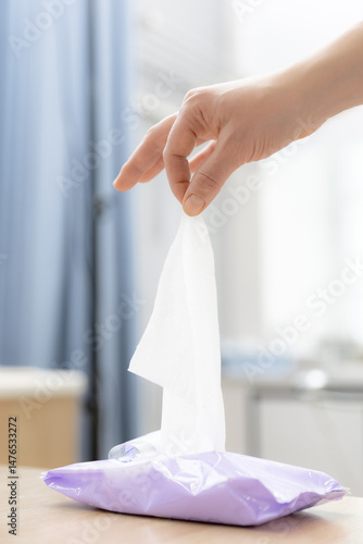 Obraz na płótnie Hand pulling wet wipe from purple package in soft light setting