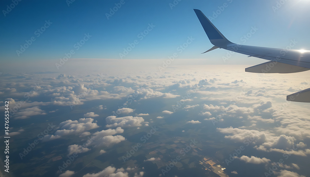 Fototapeta premium Cloudscape view from airplane wing at cruising altitude during daytime flight over countryside