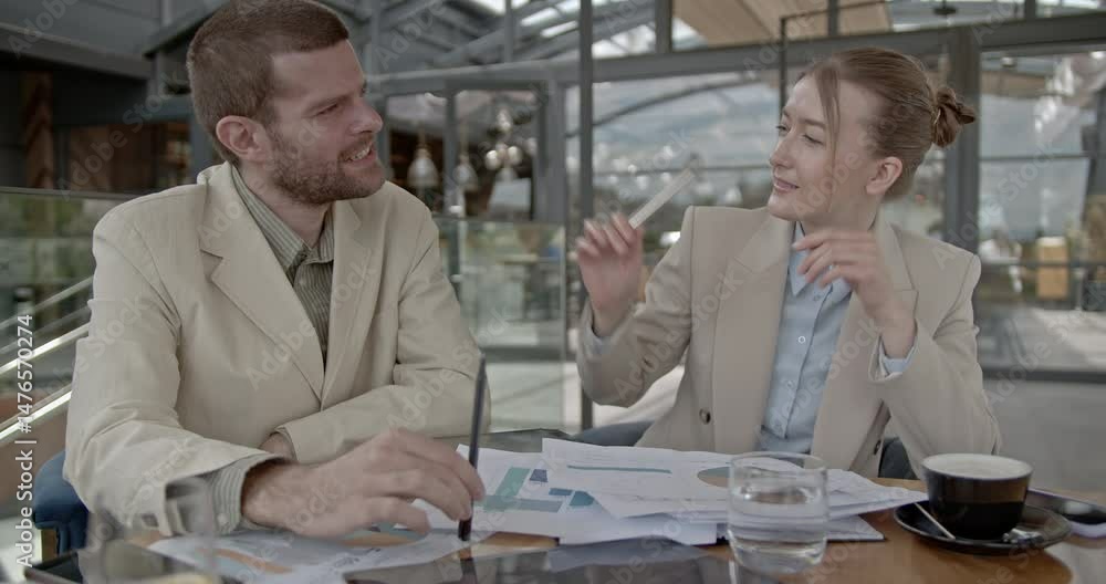 Business partners discuss company strategy, analyzing charts and graphs in a modern cafe. Collaboration and teamwork are essential for success. Business partners discuss company strategy, analyzing charts and graphs in a modern cafe. Collaboration and teamwork are essential for success.