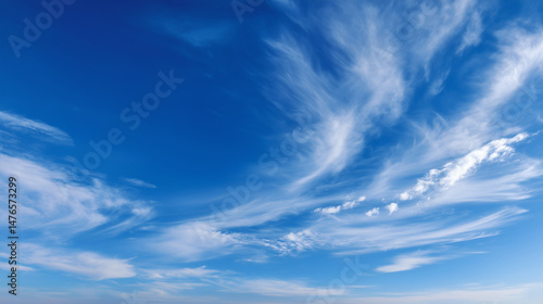 Wide open sky filled with wispy cirrus clouds stretching across a vibrant blue atmosphere. Minimal banner, wallpaper, background, screensaver