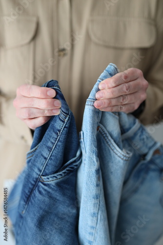 Photography A person is holding up two pairs of jeans, one blue and one white