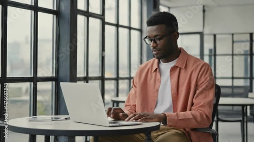 A black businessman is professionally working on his laptop at his office desk