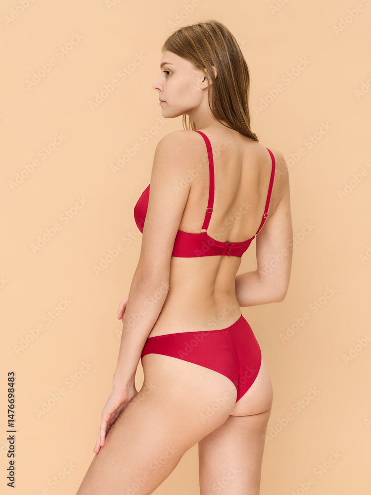 Fototapeta premium Girl model in underwear posing in studio on beige background.