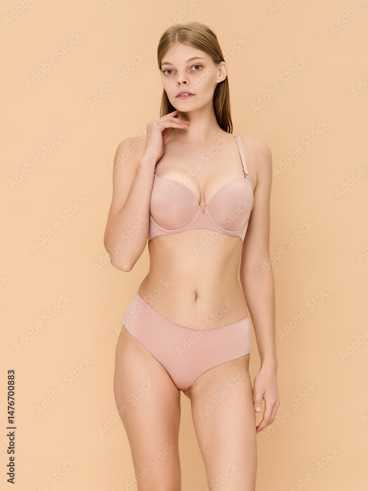 Fototapeta premium Girl model in underwear posing in studio on beige background.