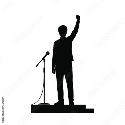 Silhouette of a speaker raising fist during a speech on a stage with a microphone