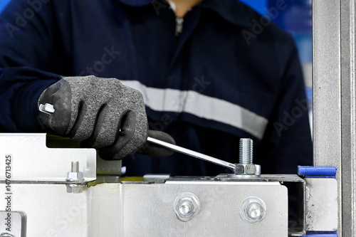 Bild auf Leinwand Factory worker tightening screw and nut with wrench